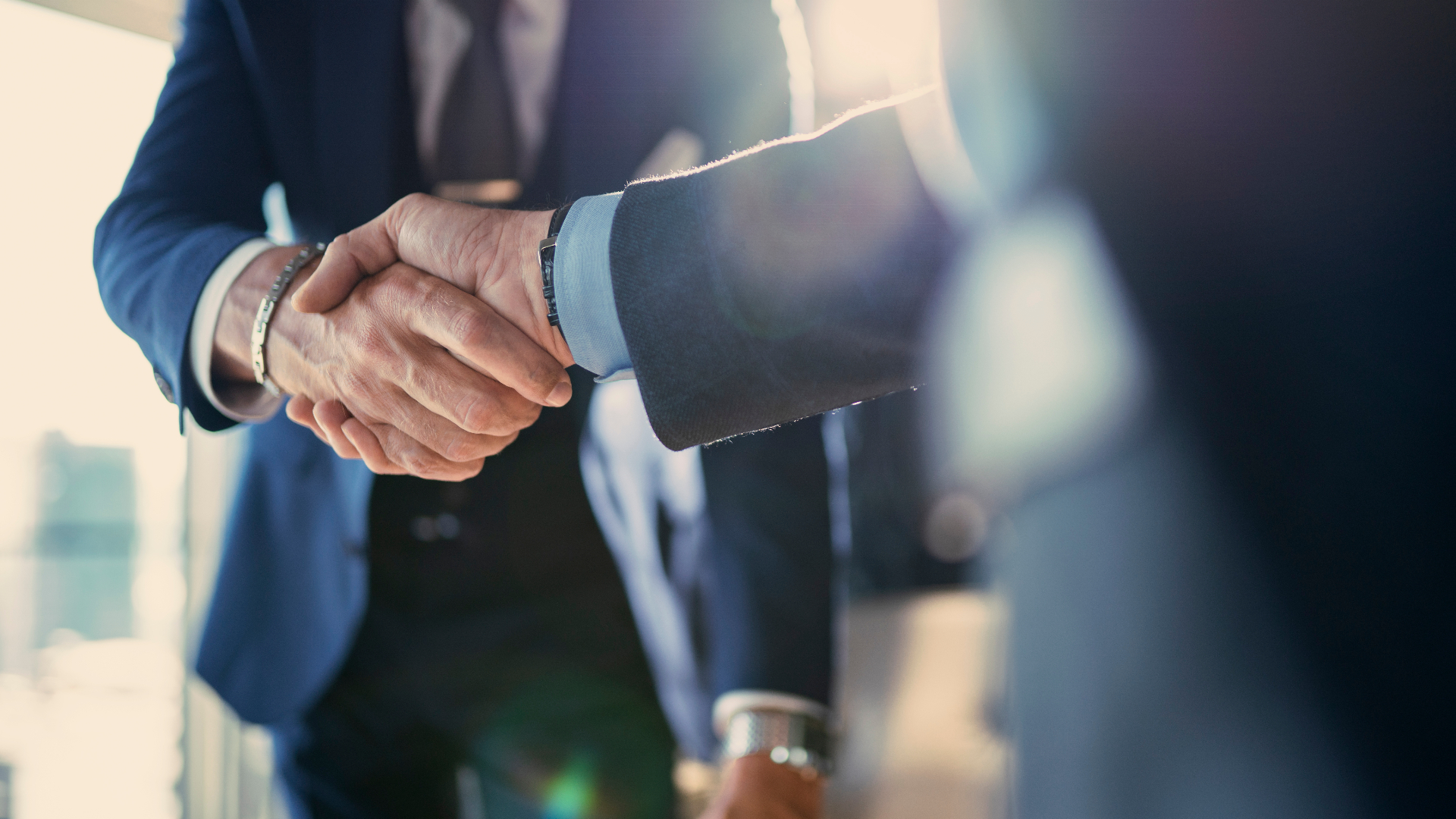 An advocate and client shake hands in a quiet private office, signaling partnership and trust.